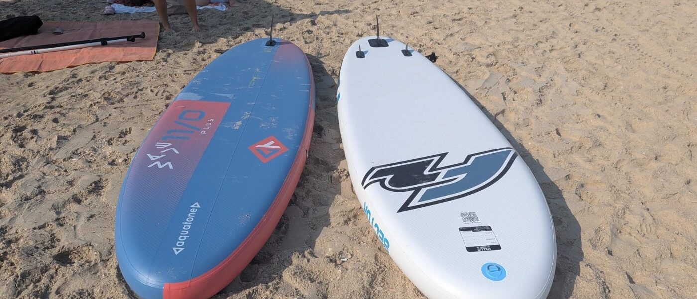 שני סאפים מתנפחים על החוף: Aquatone Wave Plus כחול-אדום ו-F2 Sector לבן