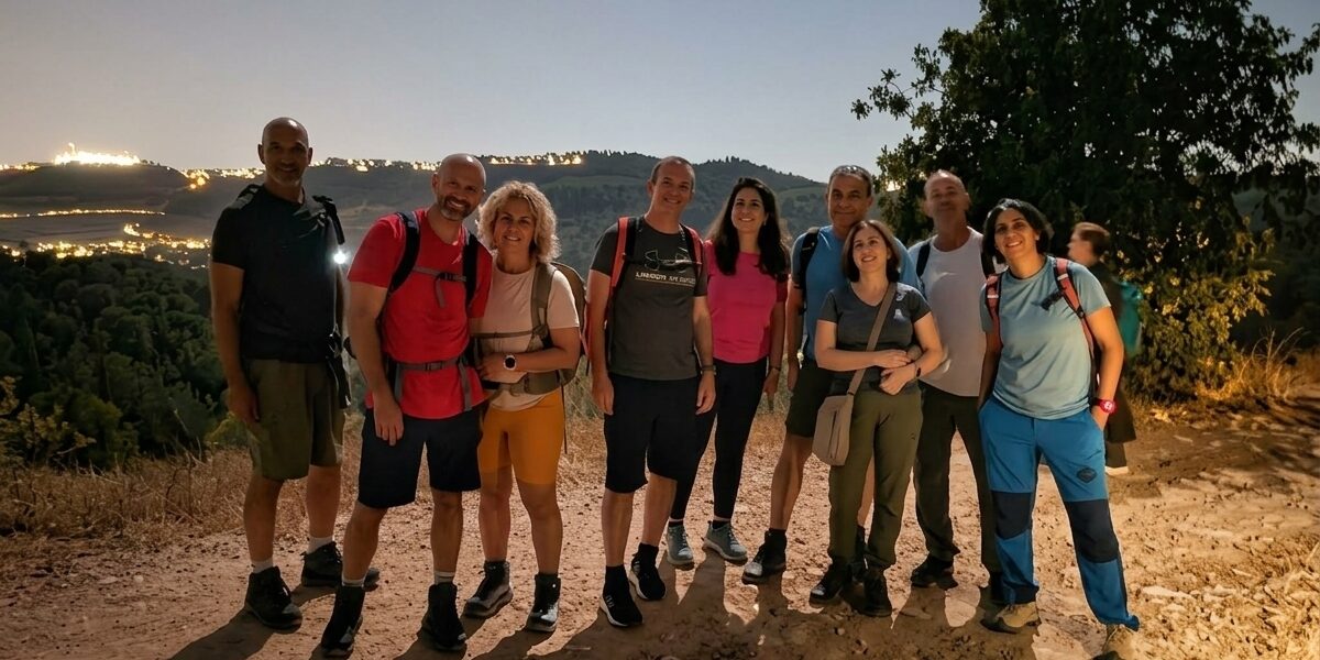קבוצת מטיילים מצטלמת בשביל עפר בהר איתן על רקע אורות ירושלים